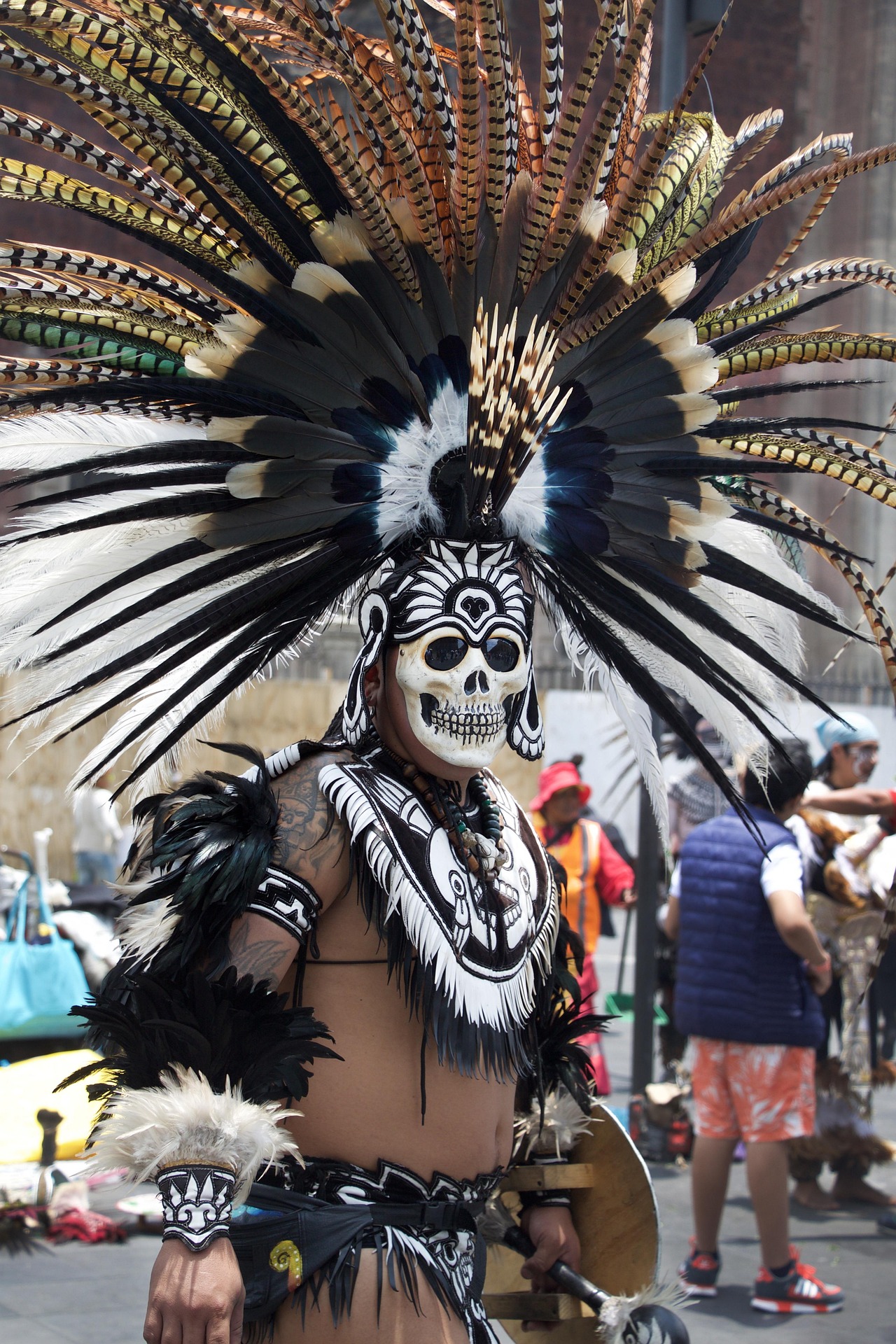 Portrait en noir et blanc d’un homme maquillé en calavera avec une coiffe représentant Quetzalcóatl, lors du Día de Muertos au Mexique