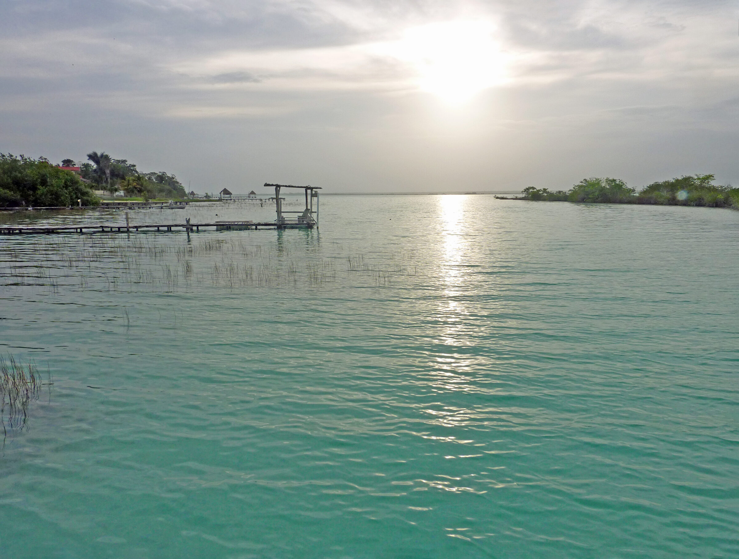 Coucher de soleil sur la lagune de Bacalar au Mexique, avec un ponton en bois et des eaux turquoise
